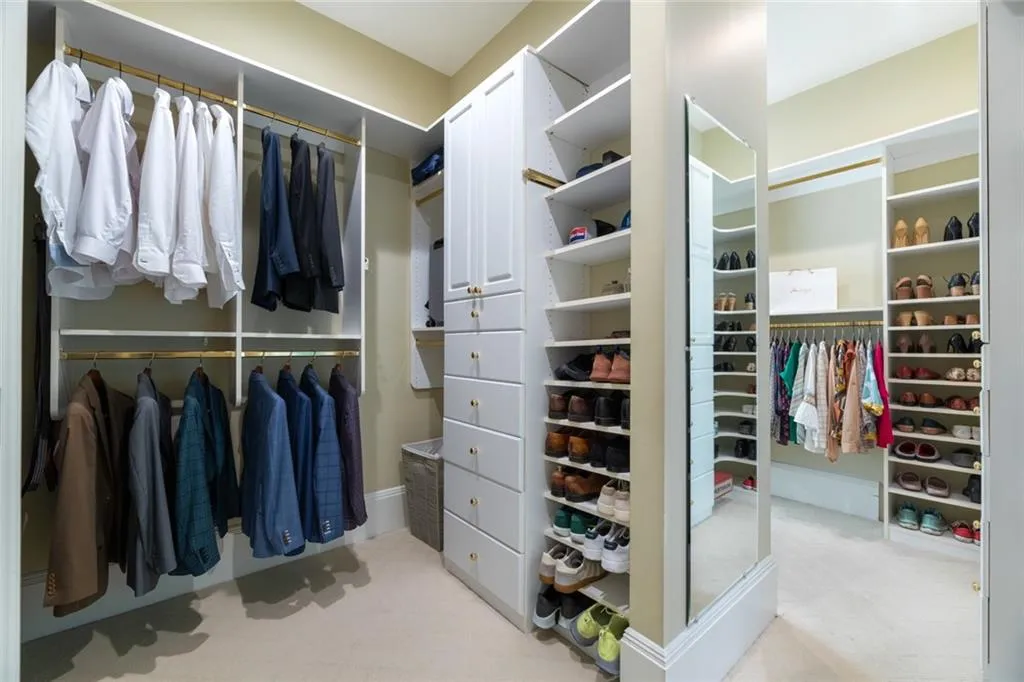 One side of the primary bedroom closet showcases custom built-ins with ample hanging space, shelving, and organized storage for a streamlined, functional design.