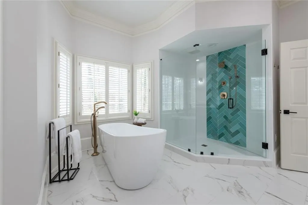 This serene primary bath is filled with natural sunlight and features a spacious walk-in shower alongside a gorgeous soaking tub. Thoughtfully designed for privacy, it offers a bright and tranquil, spa-like retreat.