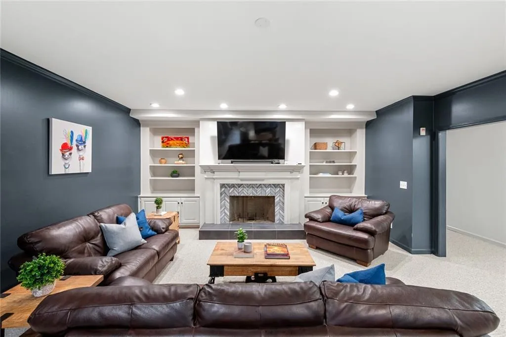 This inviting basement media area features comfortable seating and a built-in fireplace, creating the perfect space for movie nights or relaxing with family and friends. Thoughtfully designed with an open layout, it offers a cozy yet spacious environment for entertainment and leisure.