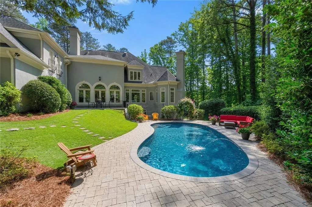 This private backyard oasis features a sparkling pool surrounded by lush landscaping and a spacious patio, perfect for relaxing or entertaining. The serene, wooded setting provides both beauty and privacy, creating a true resort-style retreat at home.