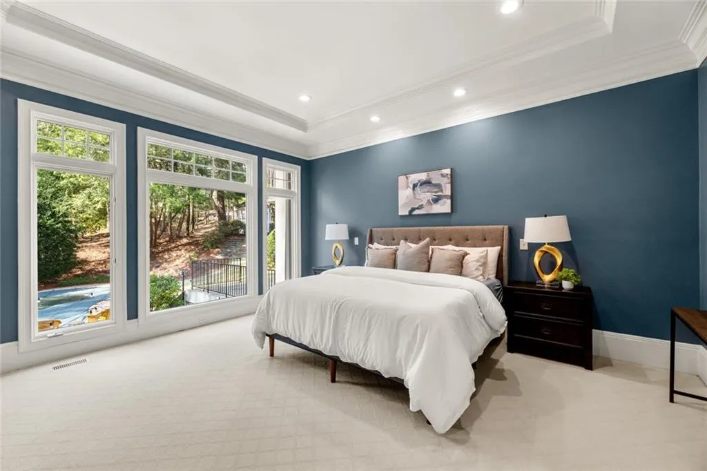 This light-filled primary suite on the main level is chock-full of natural sunlight, with expansive windows offering beautiful views of the backyard and pool. Plush carpeting adds comfort underfoot, creating a serene and inviting retreat.