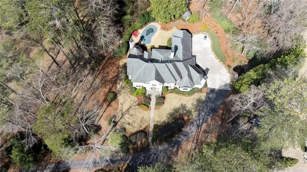This stunning aerial view showcases the home s private setting, nestled on beautifully wooded acreage with a long, winding driveway. Surrounded by mature trees and natural landscaping, the property offers exceptional seclusion and a true estate-like feel.