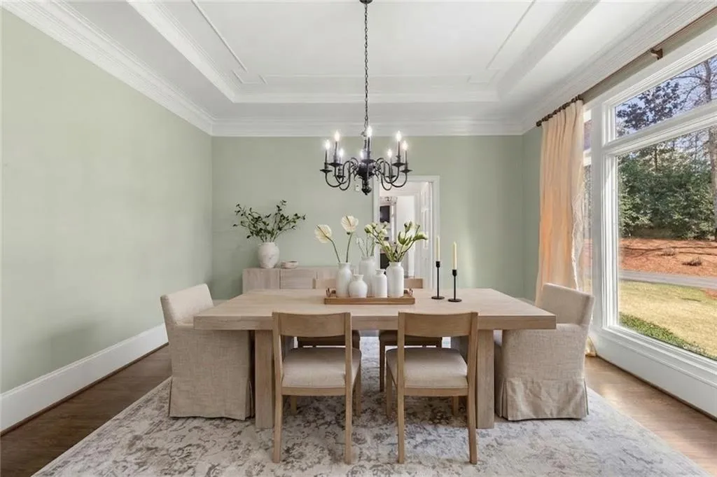 This elegant formal dining room offers a seamless flow to the butler's pantry, making it ideal for effortless entertaining. A large window frames beautiful views of the meticulously landscaped yard, adding natural light and charm to the space.