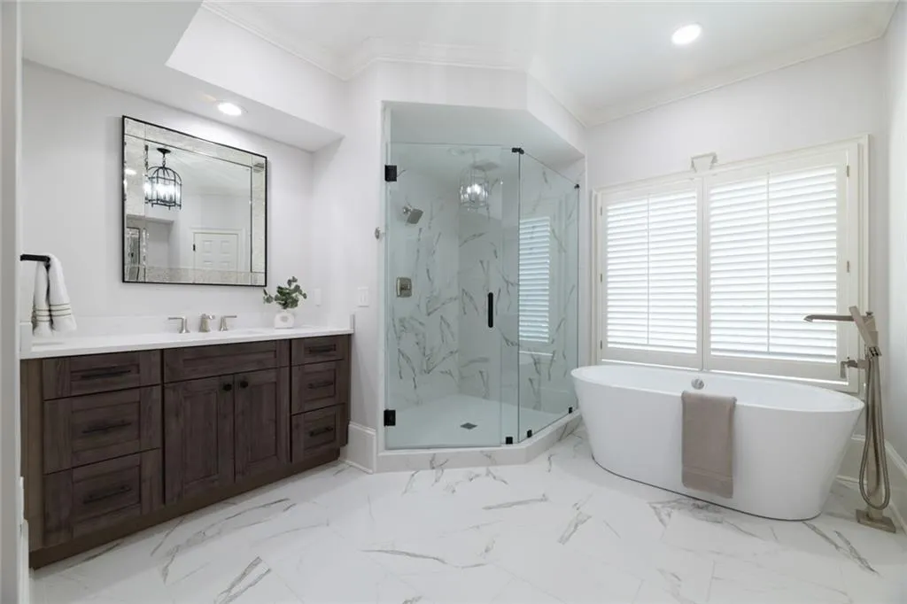 This expansive secondary primary ensuite features a spa-like bathroom with a separate glass-enclosed shower, soaking tub, and dual vanities. A spacious walk-in closet adds convenience, completing this comfortable and well-appointed retreat.