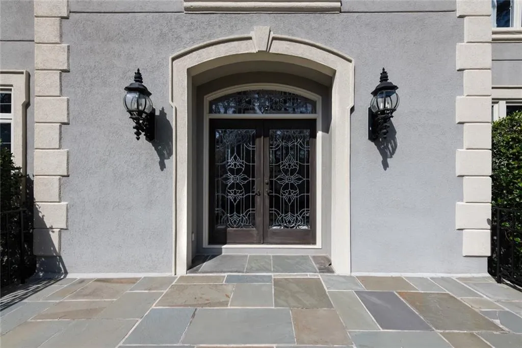 A charming front entry welcomes you with a stately arched doorway, elegant double doors, and classic lantern-style lighting. Framed by manicured hedges and a paver walkway, the entrance creates a warm and sophisticated first impression.