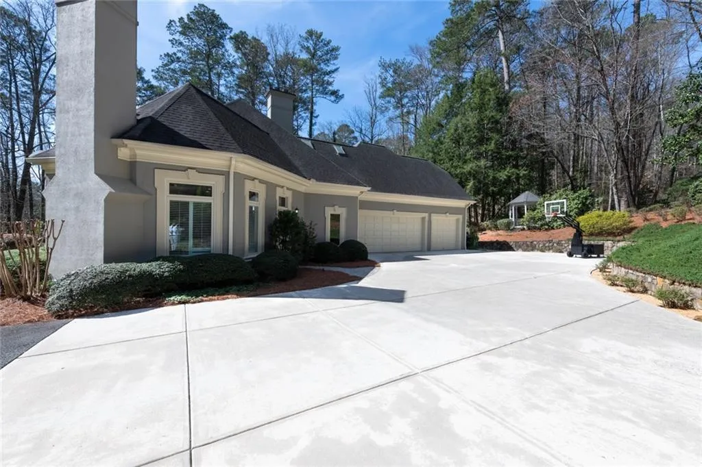 This expansive driveway offers ample additional parking and easy access to a spacious three-car garage, ideal for both everyday convenience and entertaining guests. Surrounded by mature landscaping, the setting provides a clean, welcoming approach with added privacy and curb appeal.