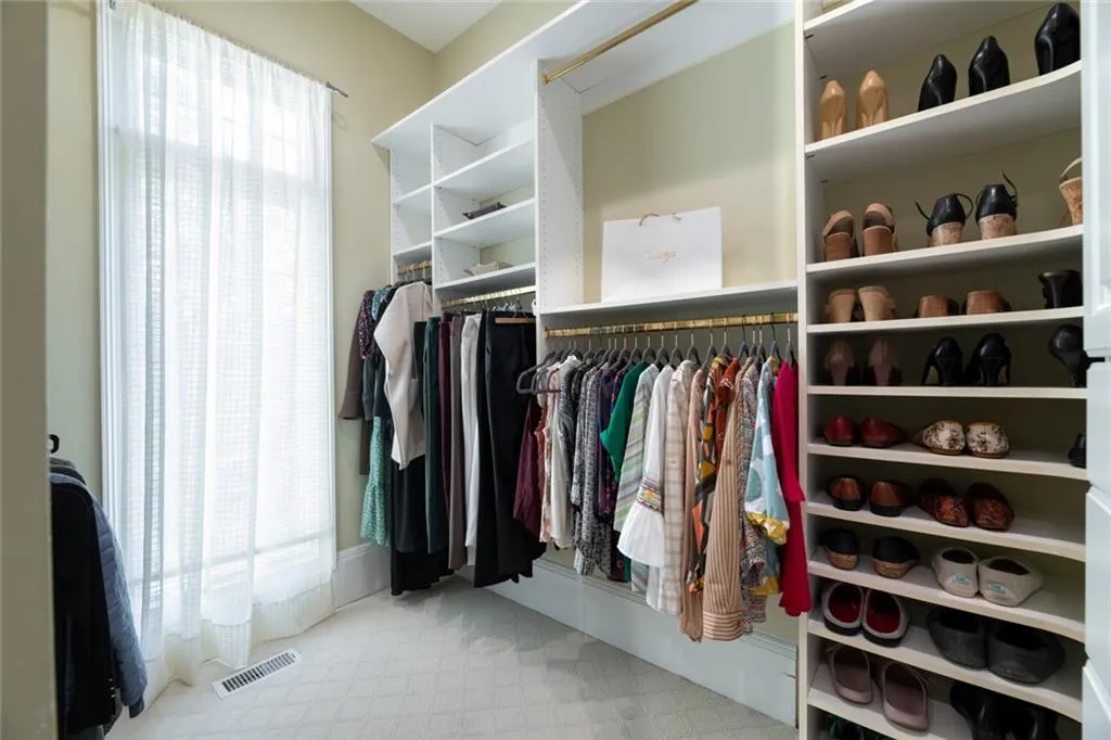 The second side of the primary bedroom walk-in closet features custom built-ins with dedicated hanging space, shelving, and organized shoe storage for maximum functionality.
