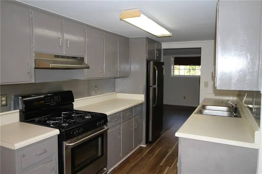 Kitchen featuring gray cabinets, a sink, gas range, and under cabinet range hood