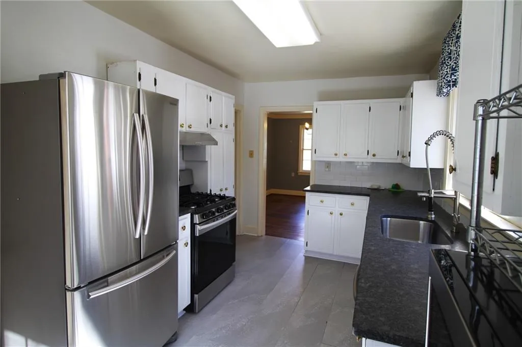 Kitchen featuring under cabinet range hood, a sink, dark countertops, and appliances with stainless steel finishes