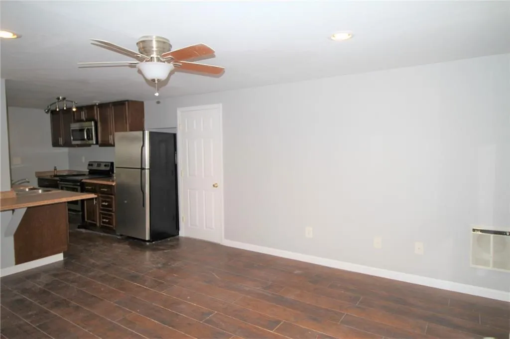 Kitchen with dark wood-style flooring, stainless steel appliances, a sink, ceiling fan, and dark brown cabinetry