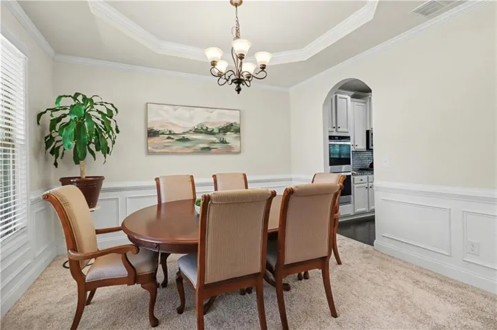 Dining area featuring wainscoting, crown molding, and a tray ceiling with a chandelier