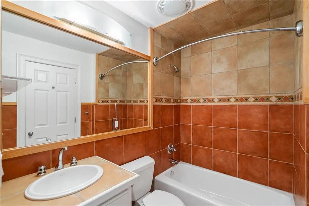 Full bathroom featuring vanity, tile walls, toilet, and tiled shower / bath combo