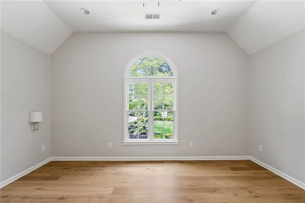 Spare room featuring light hardwood / wood-style flooring, lofted ceiling, and plenty of natural light
