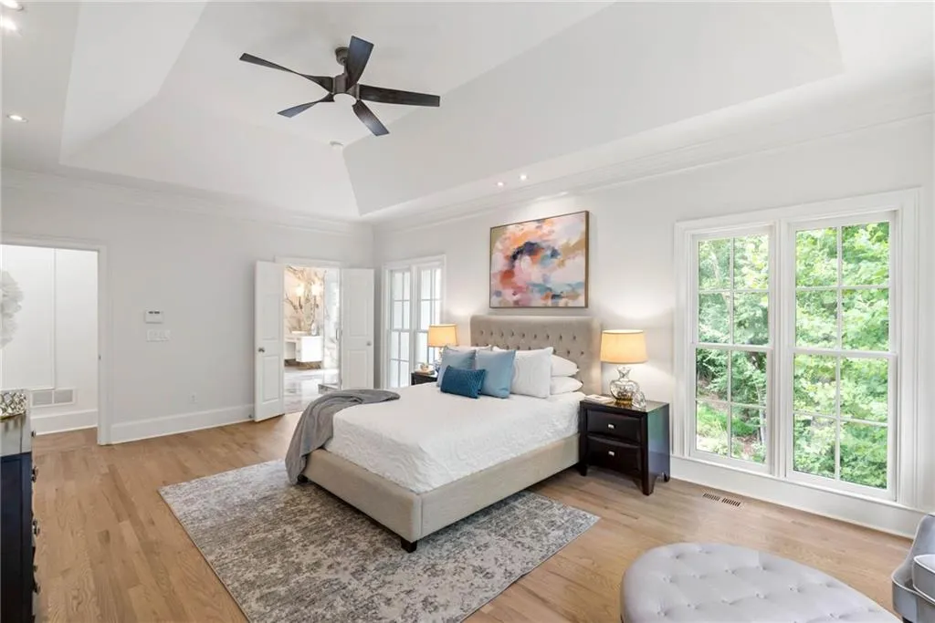 Bedroom with ceiling fan, light wood-type flooring, and a raised ceiling