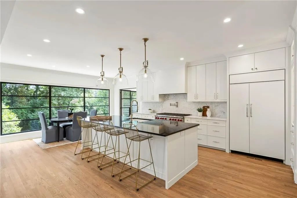 Kitchen featuring light hardwood / wood-style flooring, white cabinetry, a kitchen island with sink, tasteful backsplash, and paneled built in refrigerator