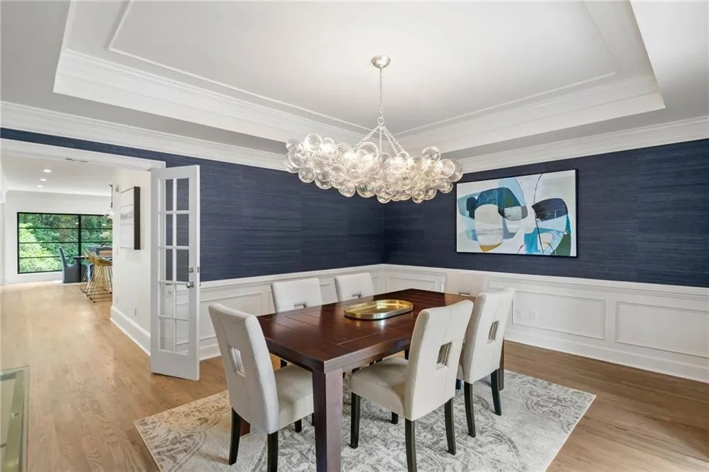 Dining area featuring a notable chandelier, a tray ceiling, crown molding, and wood-type flooring