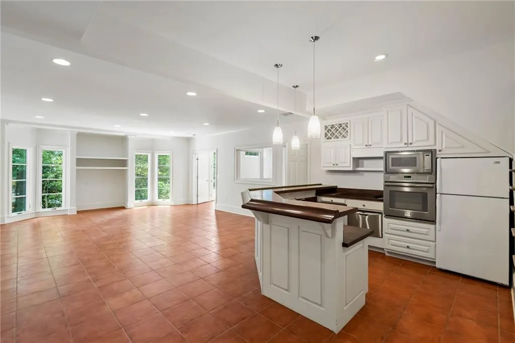 Kitchen featuring appliances with stainless steel finishes, white cabinetry, hanging light fixtures, and dark tile patterned floors
