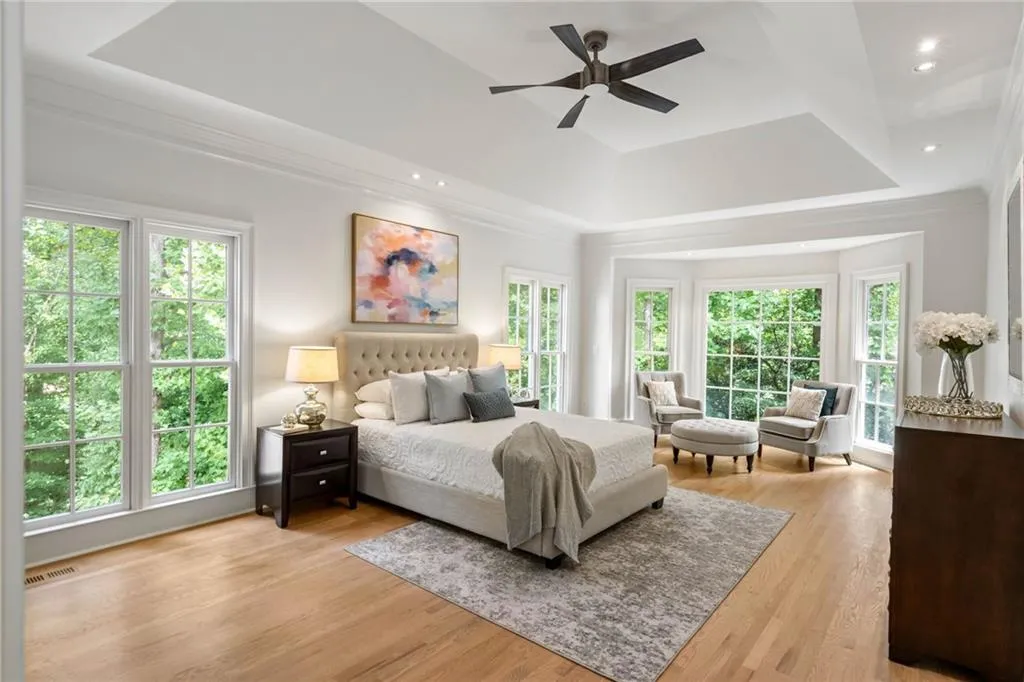Bedroom with light hardwood / wood-style floors, ceiling fan, and multiple windows