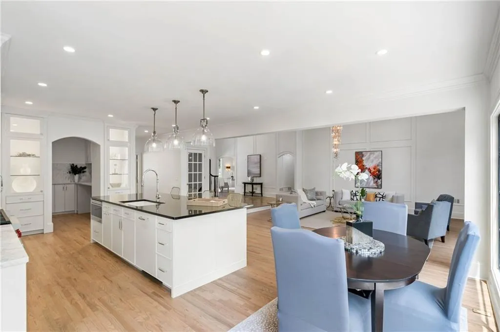 Kitchen featuring sink, an island with sink, light hardwood / wood-style floors, and white cabinetry