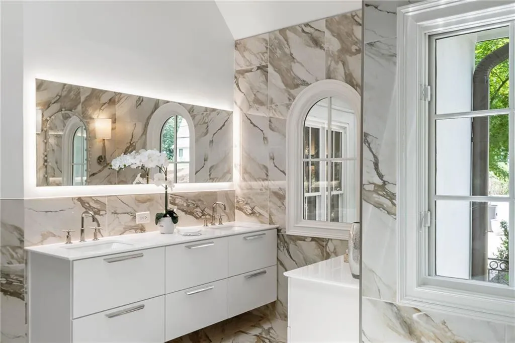 Bathroom featuring tile walls and dual vanity