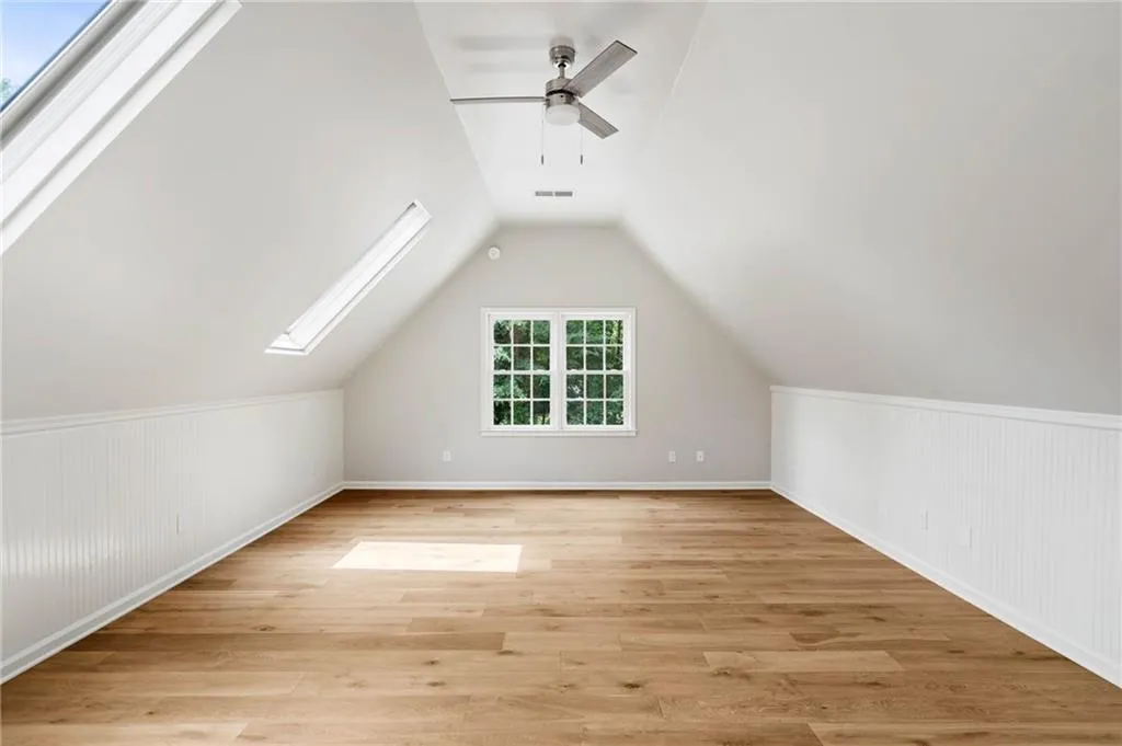 Bonus room featuring vaulted ceiling with skylight, ceiling fan, and light hardwood / wood-style floors