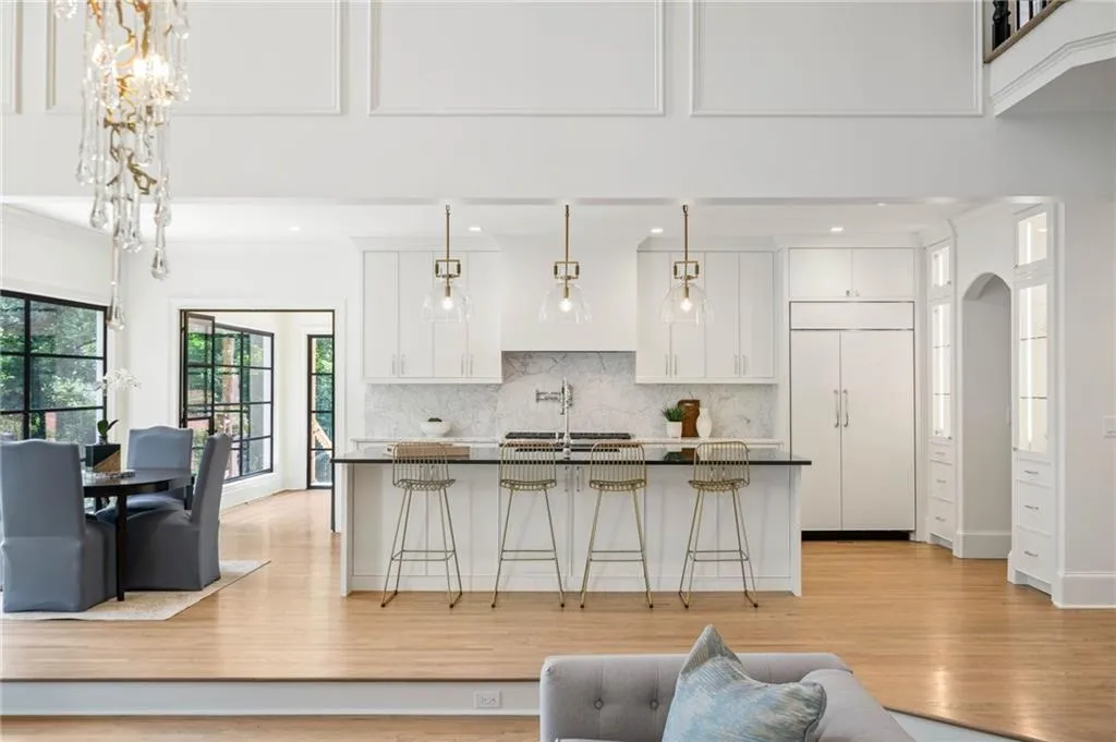 Kitchen featuring a kitchen breakfast bar, paneled refrigerator, light hardwood / wood-style floors, backsplash, and white cabinetry