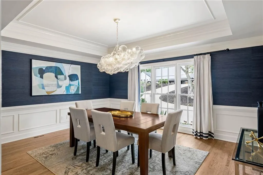 Dining area featuring a notable chandelier, light hardwood / wood-style flooring, crown molding, and a tray ceiling