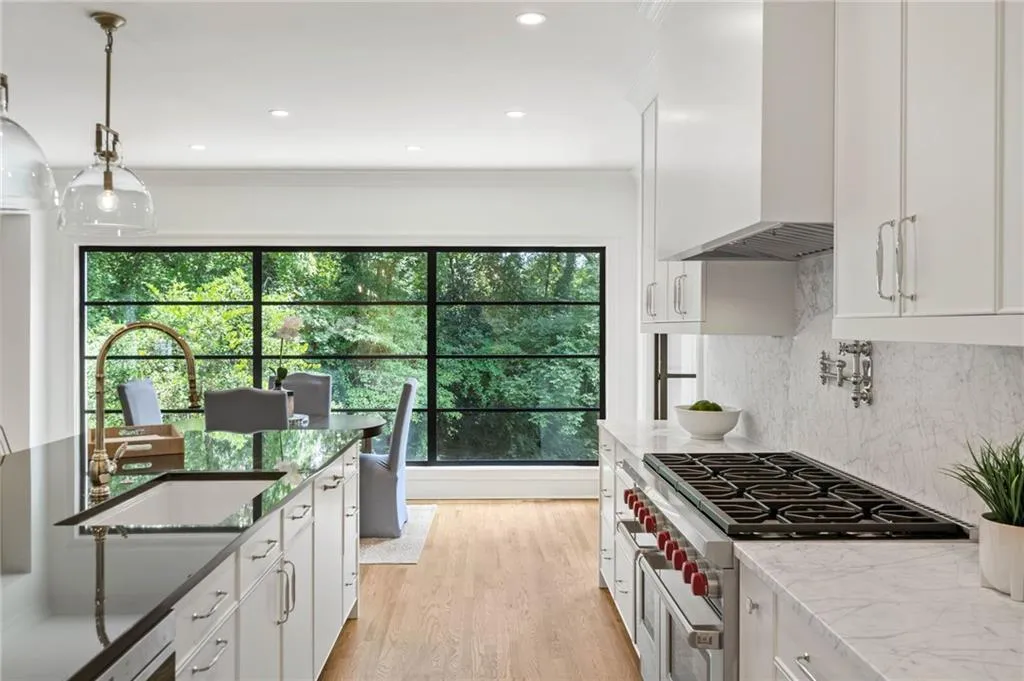 Kitchen featuring range with two ovens, light stone countertops, backsplash, light hardwood / wood-style flooring, and wall chimney exhaust hood