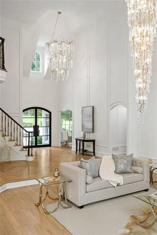 Living room featuring an inviting chandelier, a high ceiling, hardwood / wood-style floors, and french doors