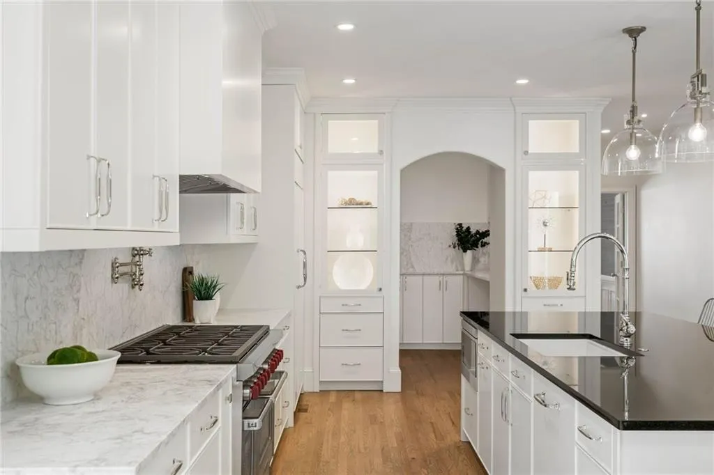Kitchen featuring decorative backsplash, white cabinets, high end stainless steel range oven, sink, and decorative light fixtures