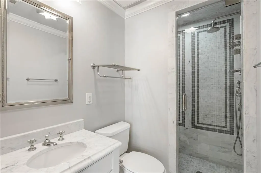 Bathroom featuring crown molding, a shower with door, vanity, and toilet