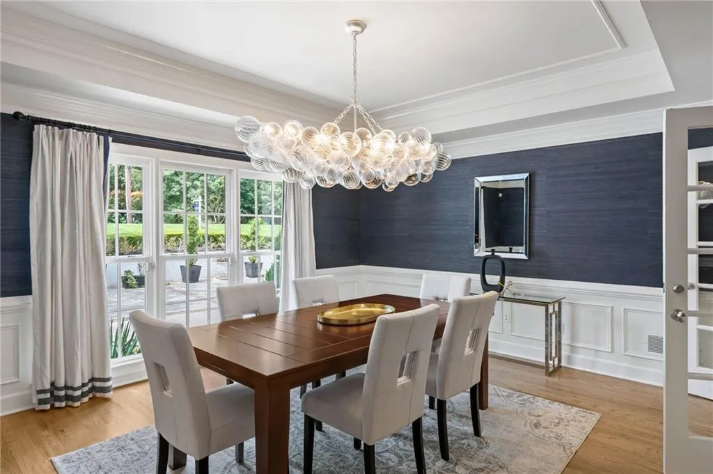 Dining area with a notable chandelier, crown molding, light wood-type flooring, and a raised ceiling