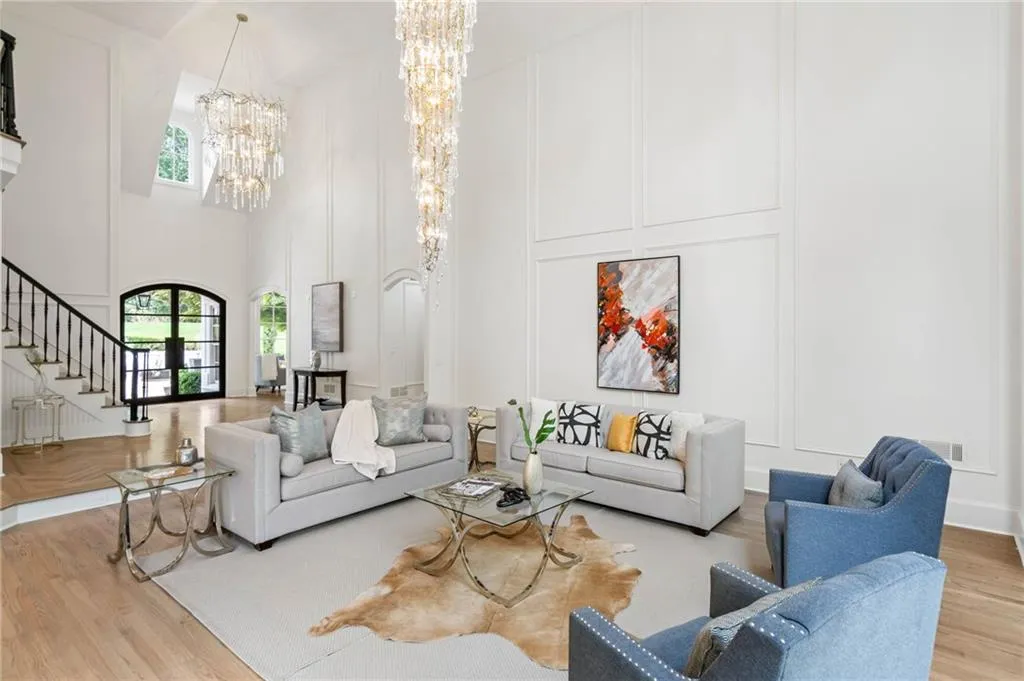 Living room featuring a towering ceiling, light hardwood / wood-style flooring, and a notable chandelier