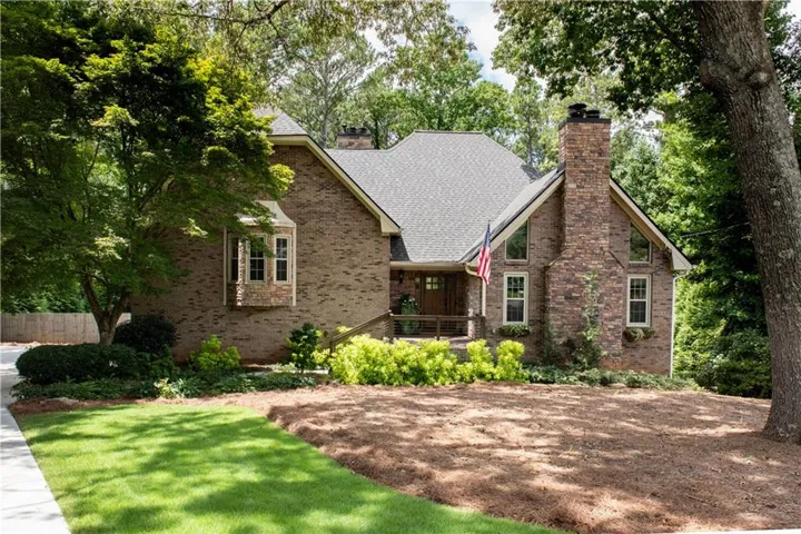 Brick Colonial residence showcasing a symmetrical façade with dual chimneys, multiple gabled rooflines, and architectural depth