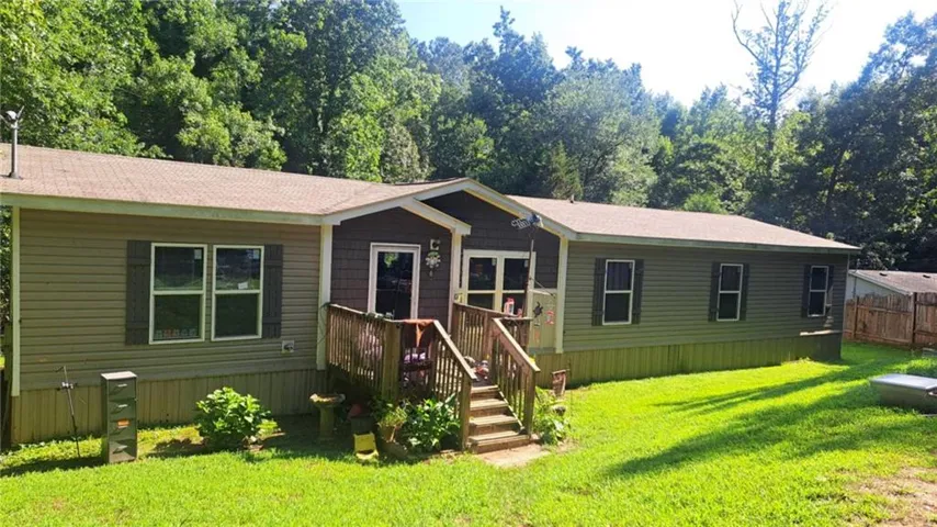 Exterior siding with contrasting shake accents, wood deck entry, and mature tree backdrop