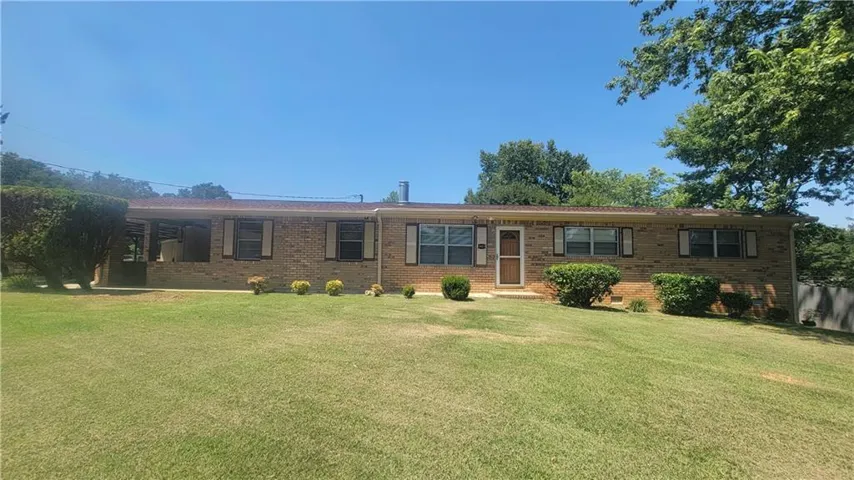 Brick exterior with an established lawn, mature landscaping, and a covered patio