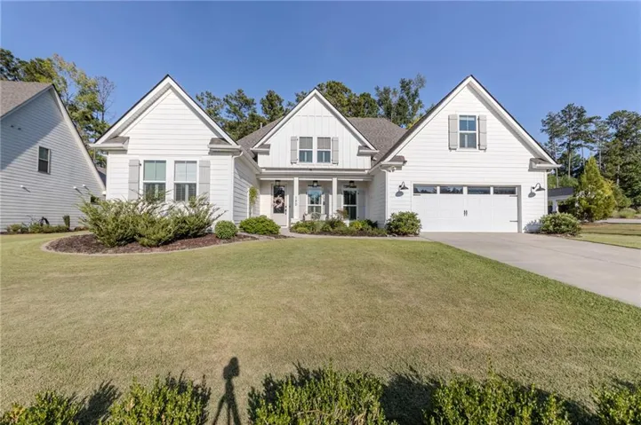 White siding exterior with a dark shingle roof, gray shutters, a two-car garage, and a concrete driveway