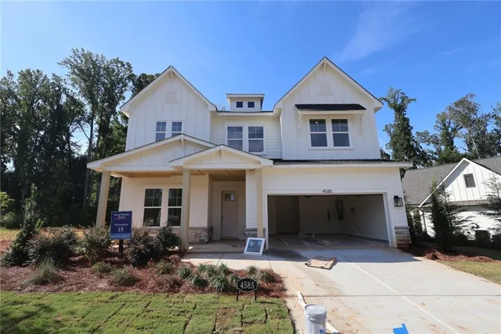 Stunning two-story Colonial-style home featuring a covered front porch, two-car garage, and manicured landscaping with mature trees