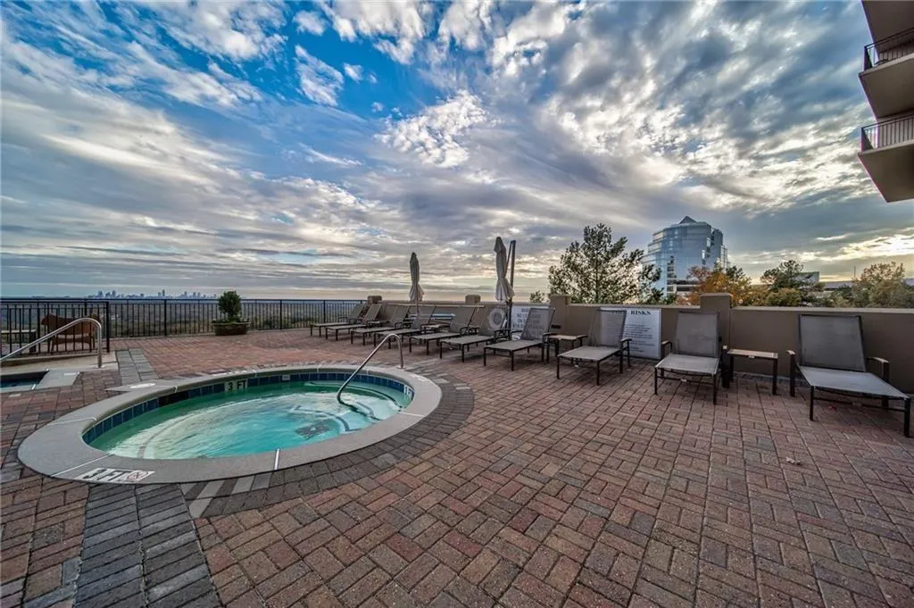 Pool at dusk featuring a hot tub and a patio