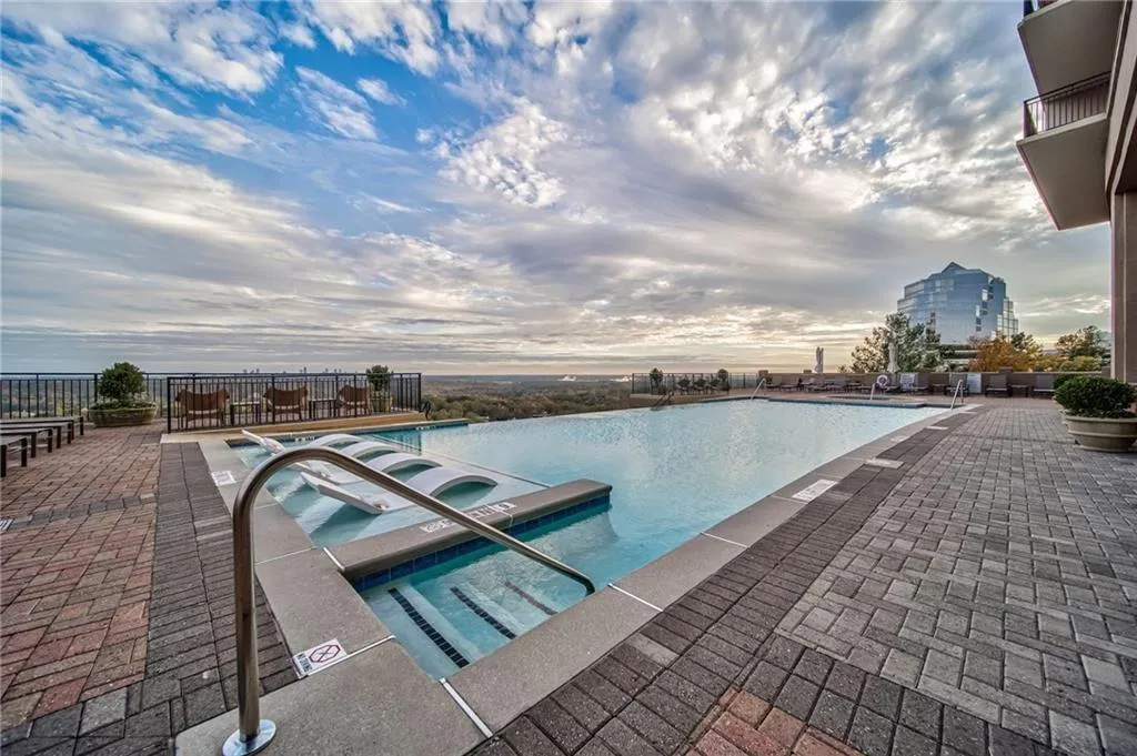 Pool at dusk featuring a patio area and a hot tub