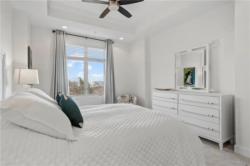 Bedroom featuring a tray ceiling, ornamental molding, light carpet, and ceiling fan