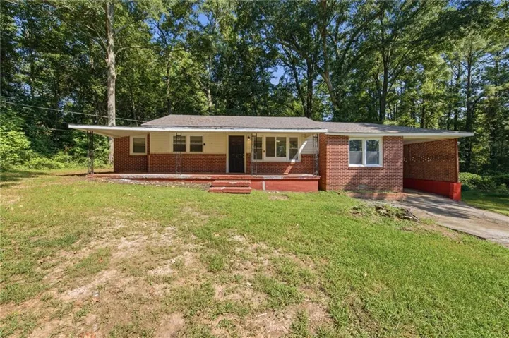 Brick exterior with a covered front porch, carport, and a sloped front yard
