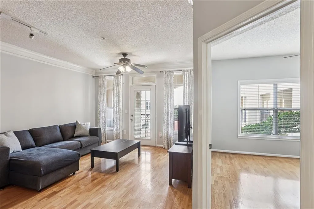 Living area featuring rail lighting, a textured ceiling, light wood-style floors, healthy amount of natural light, and a ceiling fan