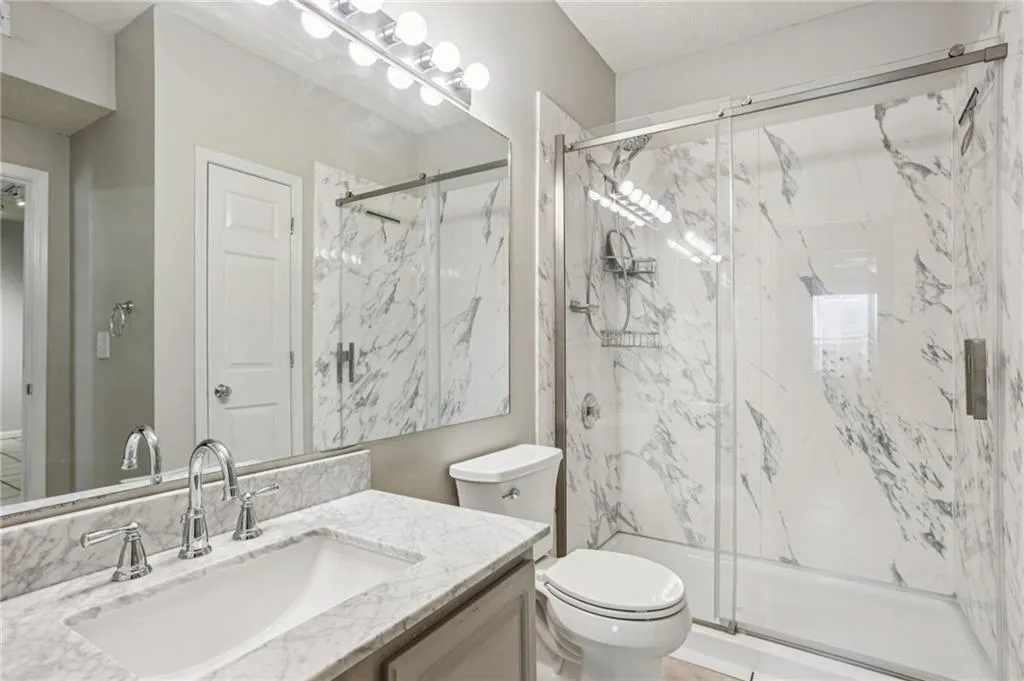 Full bath with a marble finish shower and vanity