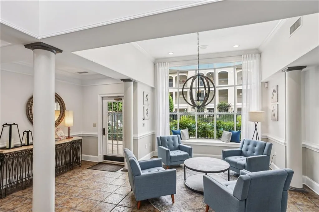 Living area featuring crown molding, healthy amount of natural light, decorative columns, and a chandelier