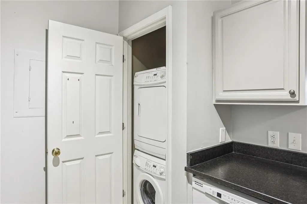 Laundry room with electric panel and estacked washer and dryer