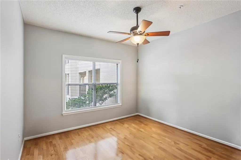 Empty room with a textured ceiling, light wood-style floors, and ceiling fan