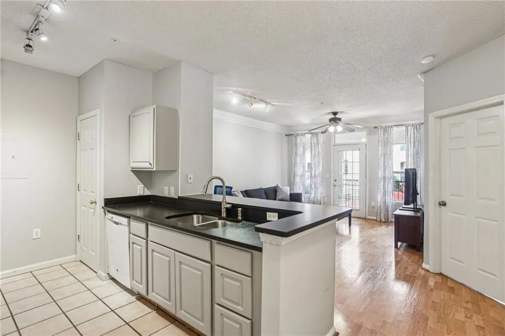 Kitchen with track lighting, dark countertops, a textured ceiling, a peninsula, and white dishwasher