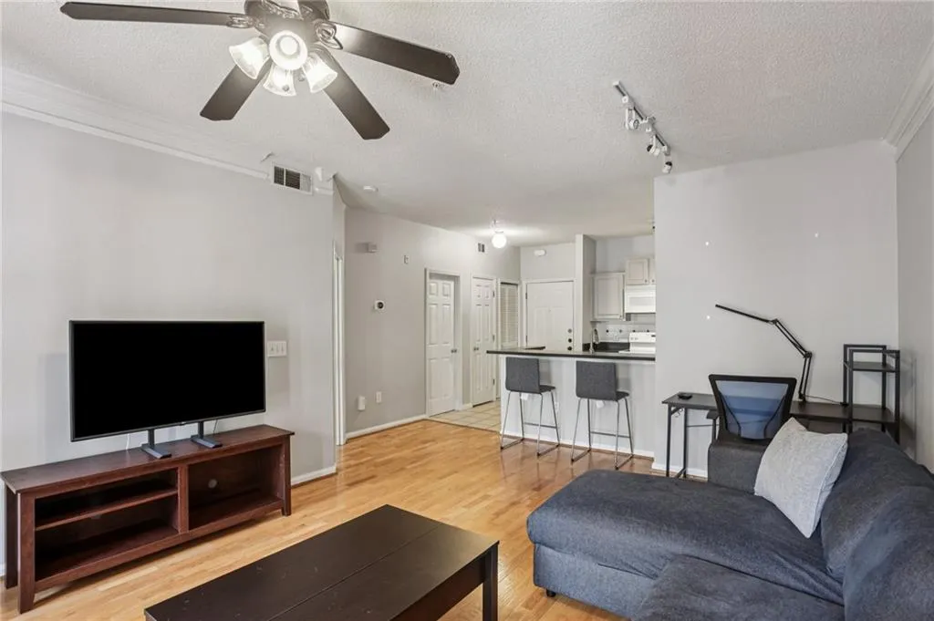 Living room featuring light wood-style floors, a textured ceiling, track lighting, and ceiling fan