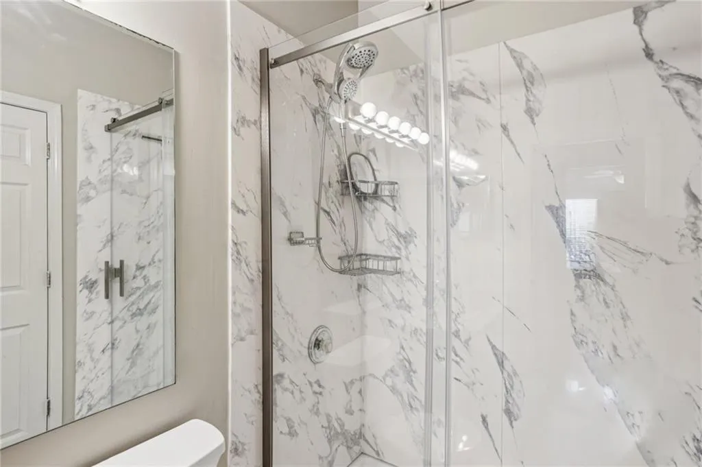 Bathroom with a marble finish shower and toilet